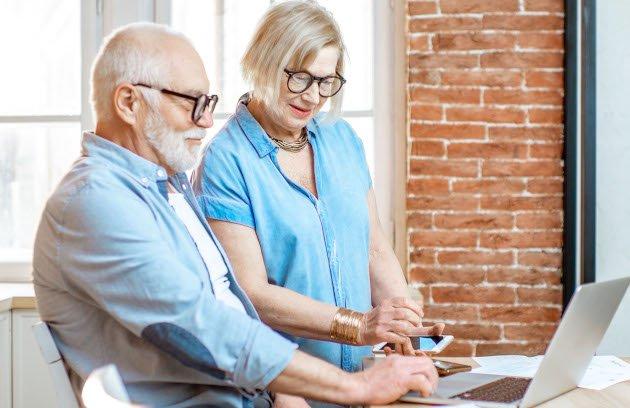 Deux personnes assises dans une cuisine, consultant un ordinateur portable et des documents pour vendre une maison