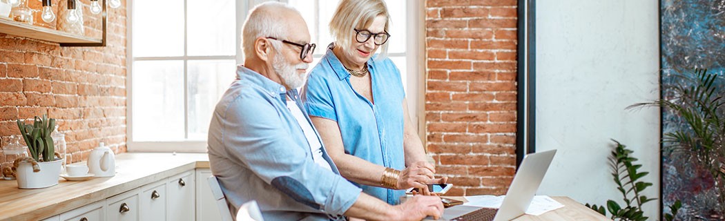 Deux personnes assises dans une cuisine, consultant un ordinateur portable et des documents pour vendre une maison