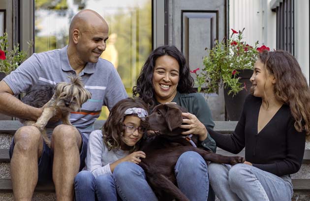 Famille devant leur maison sous un ciel ensoleillé